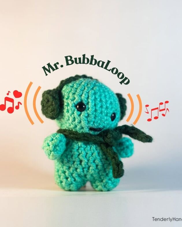 A small teal crochet monster named Mr. BubbaLoop wearing dark green headphones and a matching scarf, surrounded by orange soundwave and red musical note graphics.