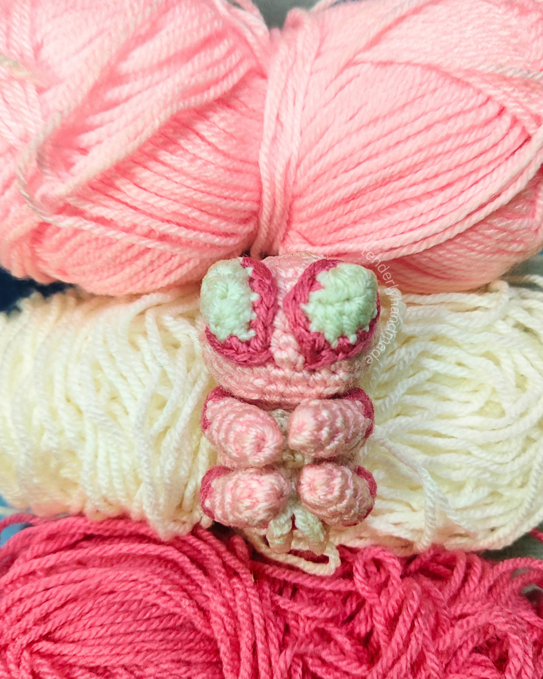 Handmade Spider-Gwen crochet amigurumi car charm sitting on pink and white yarn